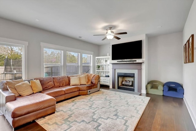 living room with ceiling fan, a fireplace, dark wood finished floors, visible vents, and baseboards
