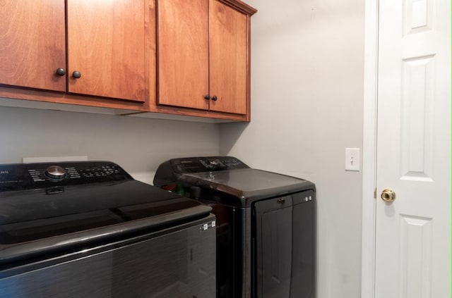 clothes washing area with cabinets and washer and clothes dryer