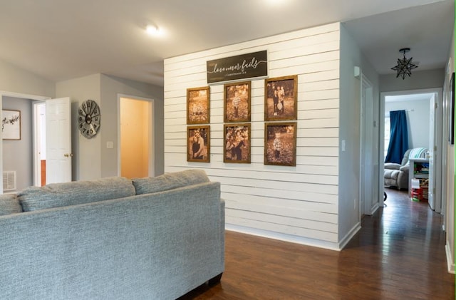 living room with dark wood-type flooring and wood walls