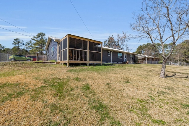 rear view of house featuring fence, a yard, and a sunroom