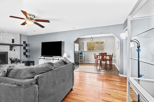 living room with hardwood / wood-style flooring, a fireplace, and ceiling fan