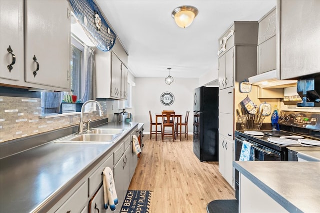 kitchen with decorative light fixtures, sink, backsplash, black appliances, and light hardwood / wood-style flooring