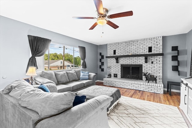 living room featuring a fireplace, ceiling fan, and light wood-type flooring