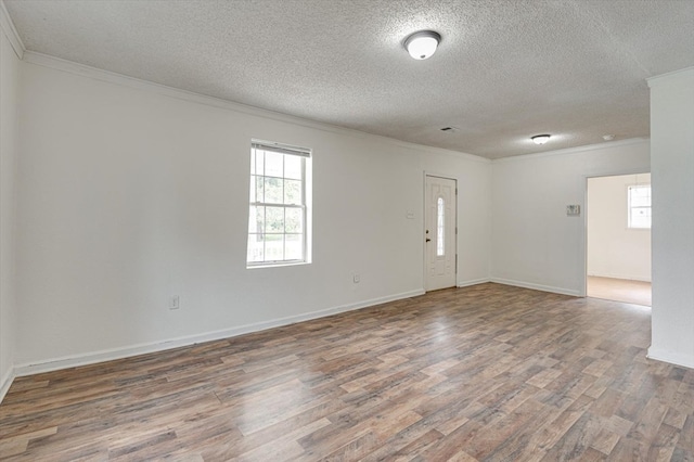 empty room with ornamental molding, dark hardwood / wood-style flooring, and a textured ceiling