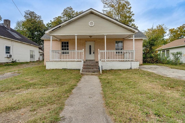 bungalow with covered porch and a front yard