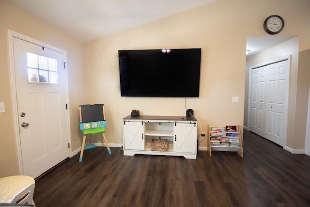 interior space featuring baseboards, dark wood-style floors, and vaulted ceiling