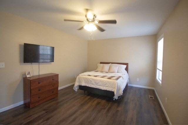 bedroom with ceiling fan, visible vents, baseboards, and dark wood-style floors