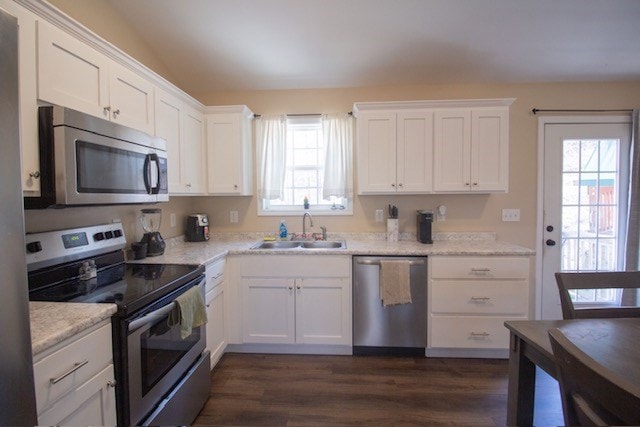 kitchen with a sink, appliances with stainless steel finishes, light countertops, and white cabinetry