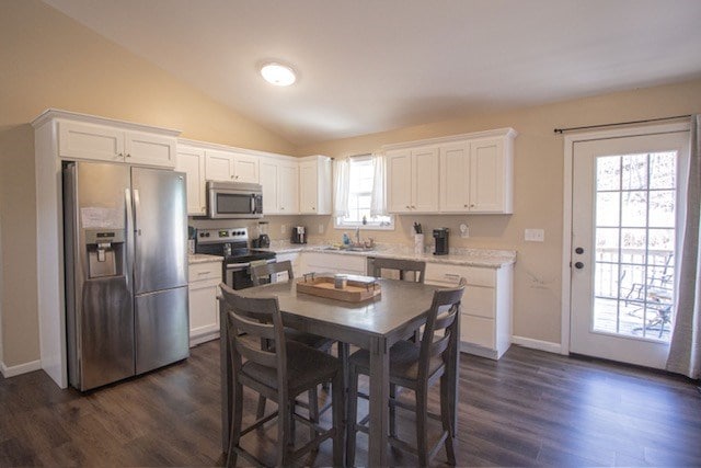 kitchen with white cabinetry, appliances with stainless steel finishes, light countertops, and vaulted ceiling