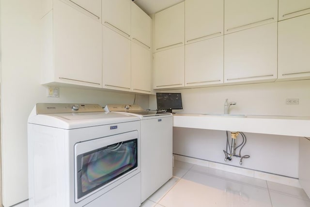 laundry area with independent washer and dryer, light tile patterned floors, and cabinets