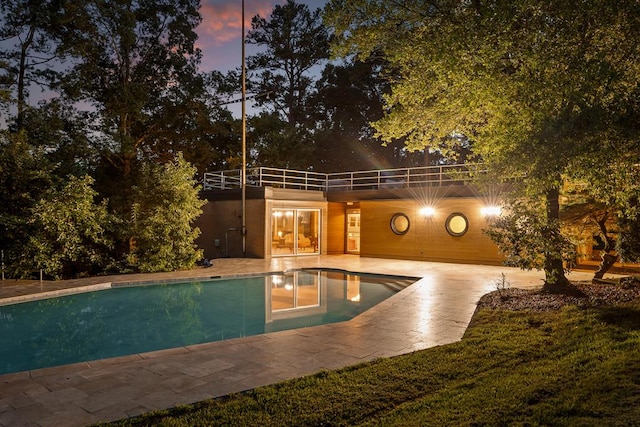 pool at dusk featuring a patio area