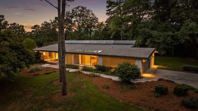 back house at dusk with a yard and a garage