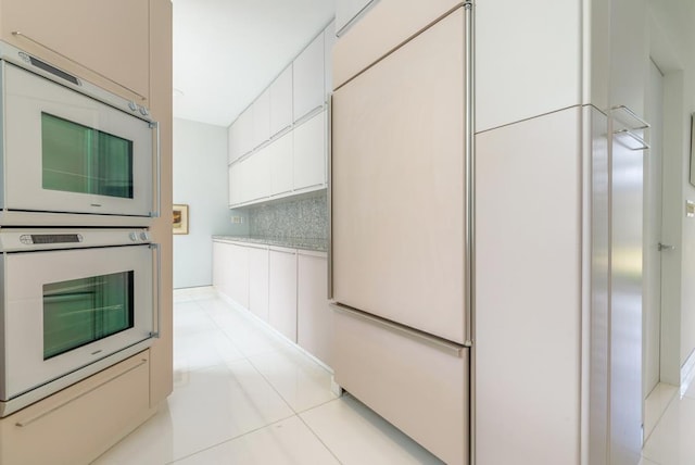 kitchen with white cabinetry, double oven, light tile patterned floors, and backsplash