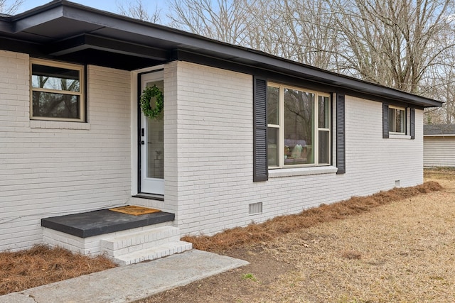 property entrance featuring crawl space and brick siding