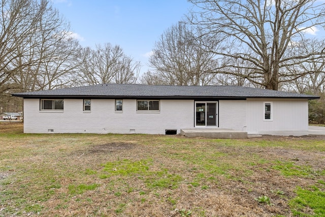 rear view of property with crawl space, brick siding, and a lawn