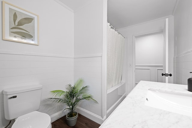 full bathroom featuring crown molding, toilet, a sink, wainscoting, and wood finished floors