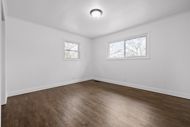 empty room featuring crown molding, dark wood-style flooring, and baseboards