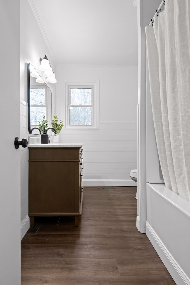 bathroom with crown molding, vanity, baseboards, wood finished floors, and toilet