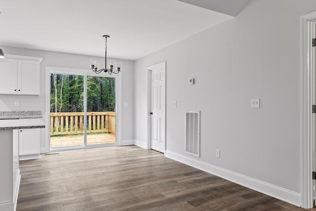 unfurnished dining area featuring dark wood-type flooring and a notable chandelier