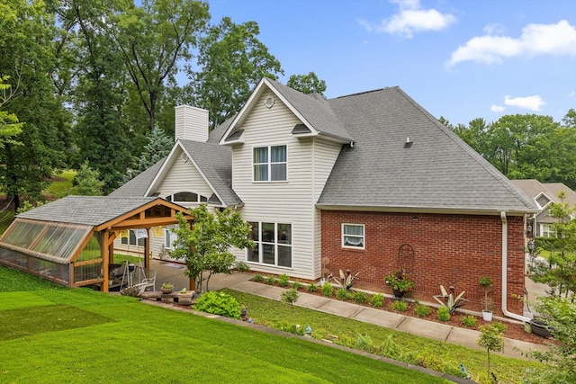 604 Lenna Ln, Dalton, GA 30720 - rear view of house with a greenhouse, brick siding, a chimney, a yard, and roof with shingles