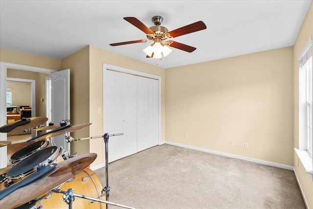 exercise area featuring light carpet and ceiling fan