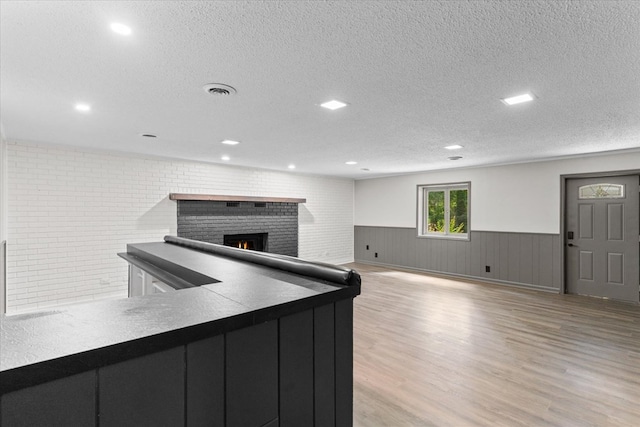 2219 Rocky Face Cir, Dalton, GA 30740 - kitchen with a wainscoted wall, a textured ceiling, light wood-type flooring, a brick fireplace, and recessed lighting