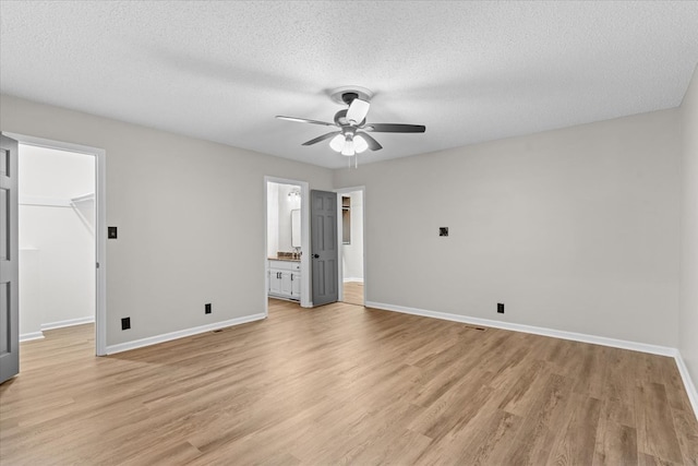 2219 Rocky Face Cir, Dalton, GA 30740 - unfurnished bedroom with a walk in closet, light wood-type flooring, a textured ceiling, ensuite bathroom, and a ceiling fan