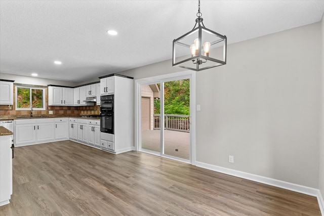 2219 Rocky Face Cir, Dalton, GA 30740 - kitchen featuring light wood-style flooring, a chandelier, decorative backsplash, under cabinet range hood, and stainless steel gas cooktop