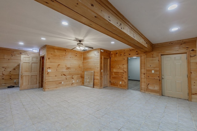 unfurnished living room featuring ceiling fan, beam ceiling, and wood walls