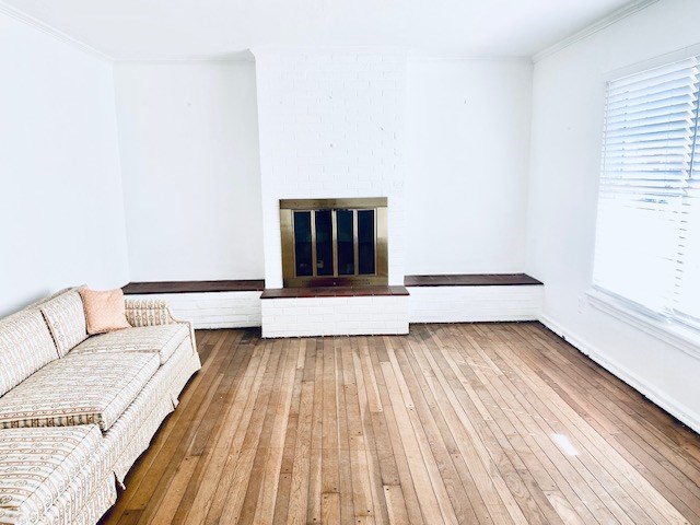 503 Williamsburg Dr, Dalton, GA 30720 - unfurnished living room featuring crown molding, hardwood / wood-style flooring, and a brick fireplace