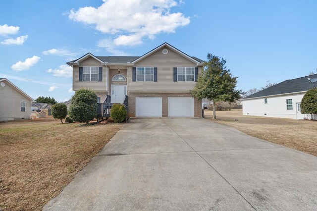 raised ranch featuring a garage and a front lawn