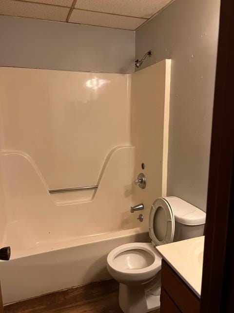 full bathroom with hardwood / wood-style flooring, a paneled ceiling, vanity, bathtub / shower combination, and toilet