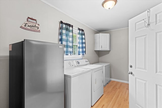 washroom featuring cabinets, ornamental molding, light wood-type flooring, and washer and clothes dryer