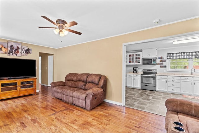 living room featuring sink, light hardwood / wood-style flooring, and ornamental molding