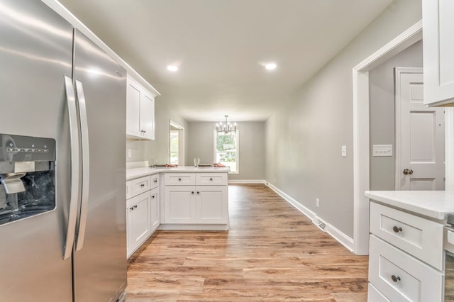 kitchen with white cabinetry, an inviting chandelier, decorative light fixtures, light hardwood / wood-style flooring, and stainless steel fridge