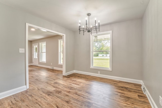 empty room with an inviting chandelier and hardwood / wood-style floors