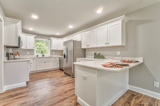 kitchen featuring sink, white cabinets, kitchen peninsula, stainless steel appliances, and light wood-type flooring