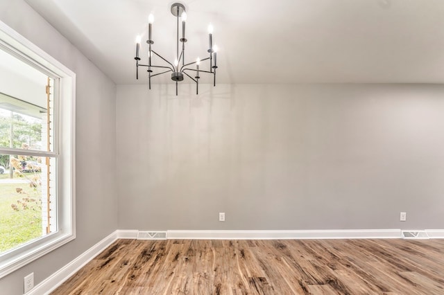 unfurnished dining area featuring an inviting chandelier, hardwood / wood-style floors, and a wealth of natural light