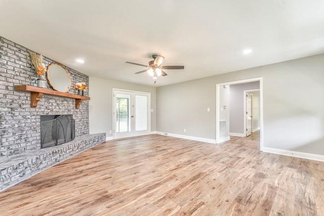 unfurnished living room with ceiling fan, a fireplace, and light hardwood / wood-style flooring