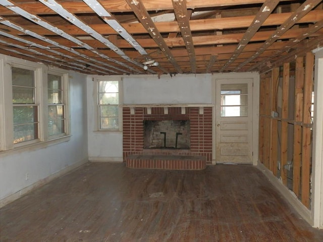 unfurnished living room featuring a brick fireplace and wood finished floors