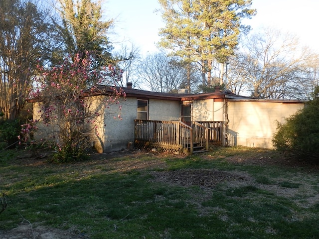 rear view of house with a lawn and stucco siding
