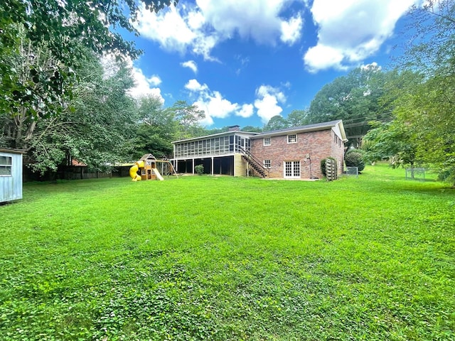 1229 Valencia Dr, Dalton, GA 30720 - back of property featuring a playground, stairway, a sunroom, brick siding, and a chimney