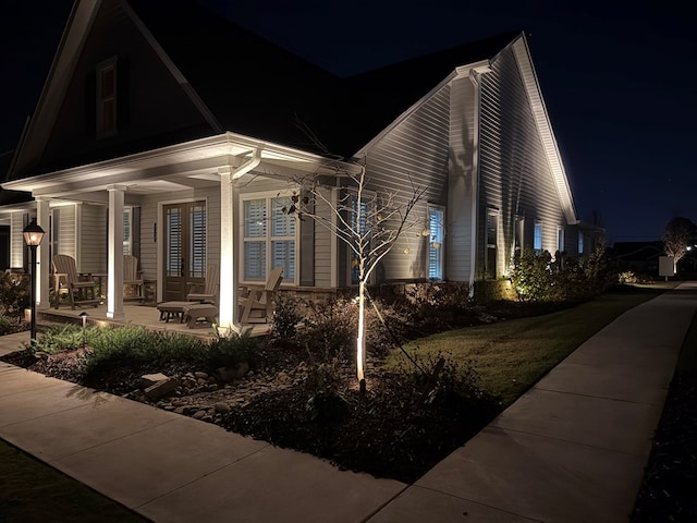 property exterior at night with covered porch