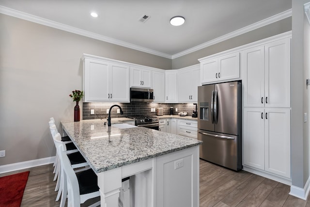 kitchen with light stone counters, kitchen peninsula, white cabinets, and appliances with stainless steel finishes