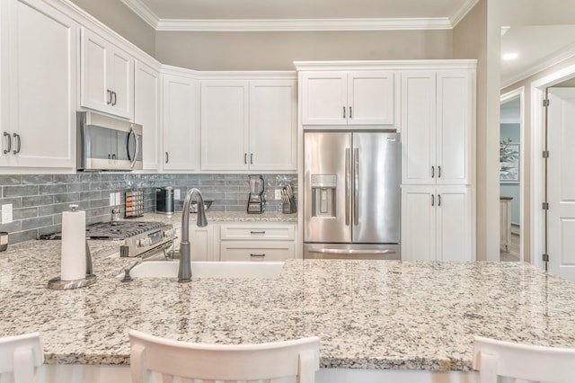 kitchen featuring stainless steel appliances, sink, a breakfast bar area, and white cabinets