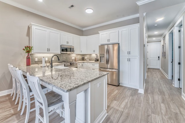 kitchen featuring white cabinetry, a kitchen bar, kitchen peninsula, and appliances with stainless steel finishes