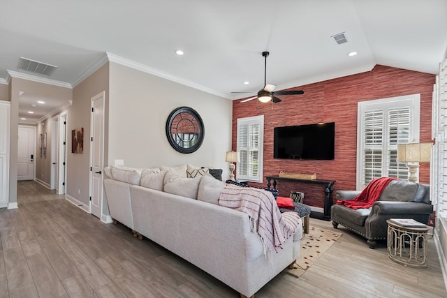 living room featuring crown molding, a wealth of natural light, and light hardwood / wood-style flooring