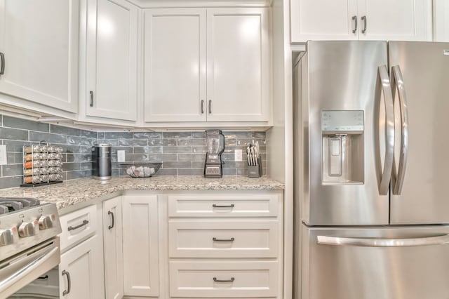 kitchen with tasteful backsplash, white cabinetry, appliances with stainless steel finishes, and light stone countertops