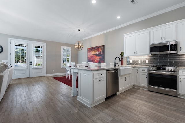 kitchen featuring sink, appliances with stainless steel finishes, hanging light fixtures, white cabinets, and kitchen peninsula