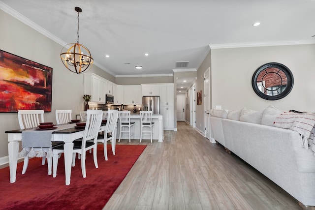 dining room featuring an inviting chandelier, crown molding, and light hardwood / wood-style flooring